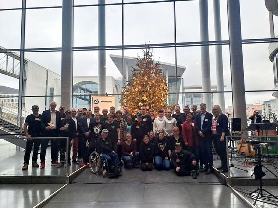 MdB Christoph Schmid steht zusammen mit der Gruppe der Lebenshilfe vor dem Weihnachtsbaum der Lebenshilfe